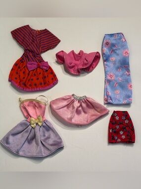 Six Barbie clothes: tops, dresses and skirts in bright prints and solids.